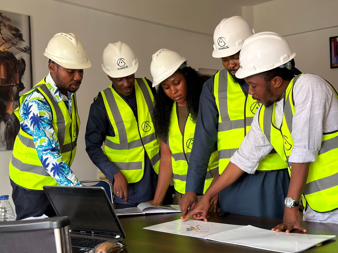 Mon offre Group of engineers in safety gear reviewing blueprints indoors.